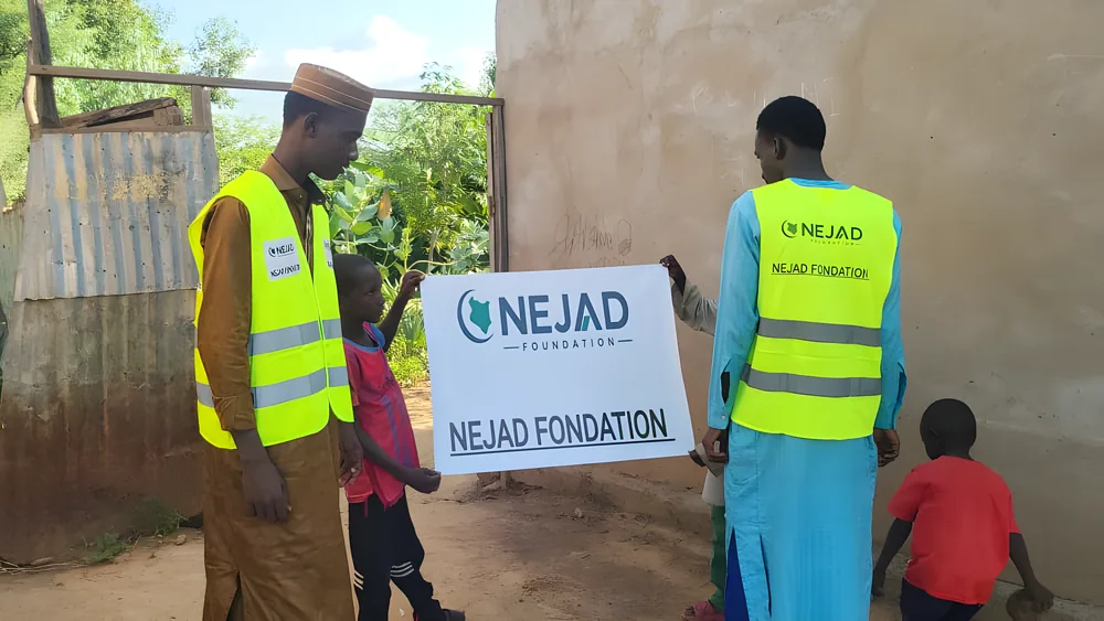 NEJAD volunteers with children holding the foundation's banner